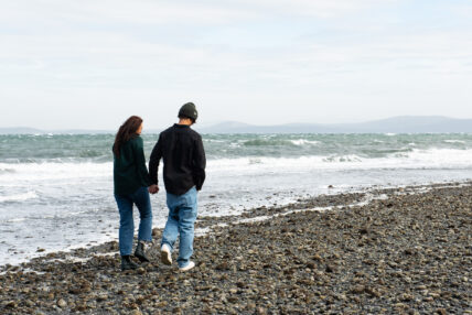 a couple walking on the beach holding hands